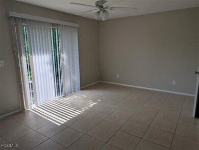 Tiled empty room with a ceiling fan and baseboards