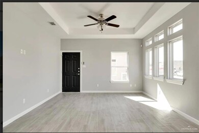 Entrance foyer with a raised ceiling, light wood-type flooring, and ceiling fan