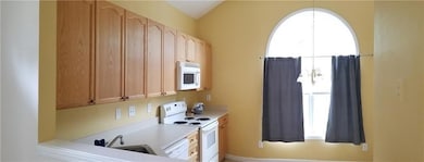Kitchen with plenty of natural light, white appliances, light countertops, and light brown cabinets