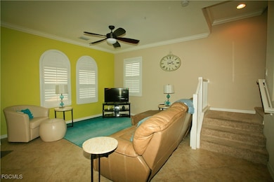 Living room featuring crown molding, ceiling fan, carpet, and stairway
