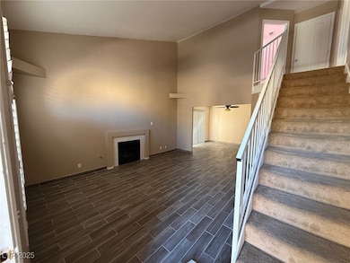 Stairs with a fireplace, a ceiling fan, wood finish floors, and a high ceiling