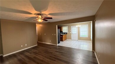 Empty room with a chandelier, wood finished floors, a textured ceiling, and a ceiling fan