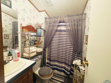 Full bathroom featuring wallpapered walls, a textured ceiling, vanity, and a shower with curtain
