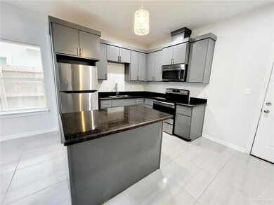 Kitchen featuring a sink, stainless steel appliances, gray cabinets, baseboards, and light tile patterned flooring