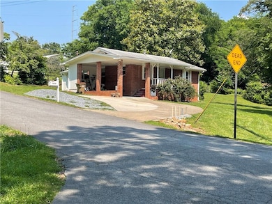 Bungalow-style home featuring covered porch, a front yard, brick siding, and driveway