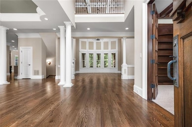 Foyer entrance featuring ornamental molding, ornate columns, wood finished floors, recessed lighting, and baseboards