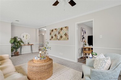 Carpeted living room with ceiling fan and ornamental molding
