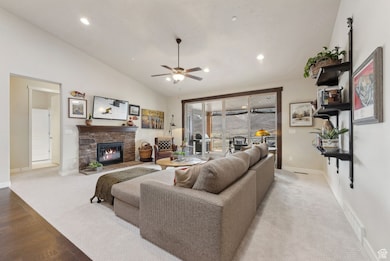 Living area featuring a fireplace, lofted ceiling, baseboards, visible vents, and ceiling fan