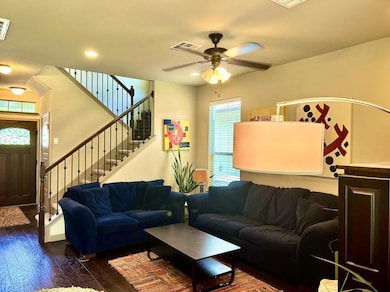 Living area featuring a ceiling fan, dark wood-ty