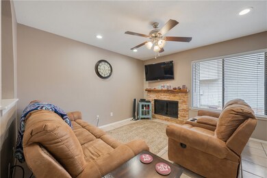 Living area with a fireplace, ceiling fan, light t