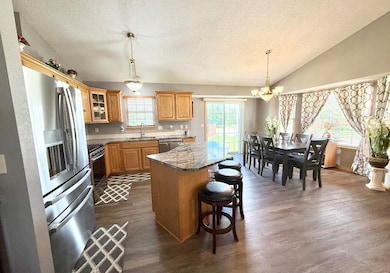 Kitchen with a sink, appliances with stainless steel finishes, a textured ceiling, a chandelier, and a center island