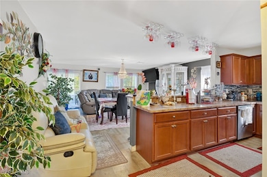 Kitchen featuring light wood-style flooring, a peninsula, brown cabinetry, and stainless steel dishwasher