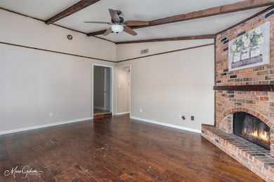 Unfurnished living room featuring dark wood-type flooring, a ceiling fan, and a brick fireplace