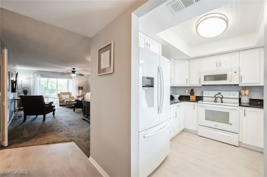 Kitchen featuring white appliances, dark counterto