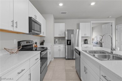Kitchen featuring white cabinetry, sink, light til