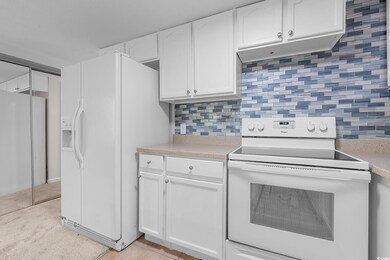 Kitchen featuring white appliances, light countertops, white cabinets, decorative backsplash, and light tile patterned flooring