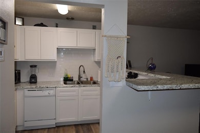 Kitchen with dishwasher, white cabinetry, tasteful backsplash, and a textured ceiling