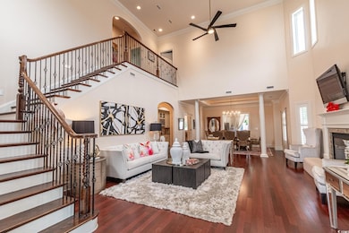 Living room with a ceiling fan, a chandelier, a towering ceiling, stairway, and dark wood-style flooring
