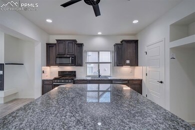 Kitchen with stainless steel appliances, a ceiling fan, decorative backsplash, dark brown cabinetry, and recessed lighting