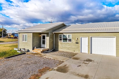 View of front of property featuring a metal roof, a garage, and driveway