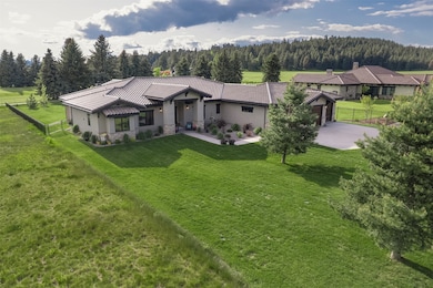 View of front of property featuring a wooded view, a tile roof, stucco siding, concrete driveway, and a garage