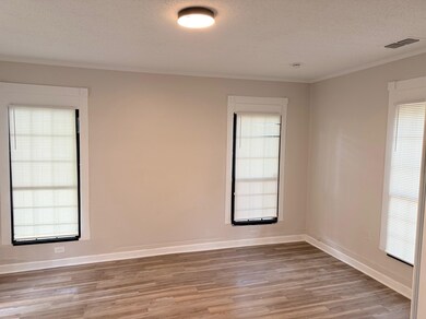 Empty room featuring light wood-style floors, a textured ceiling, crown molding, and baseboards