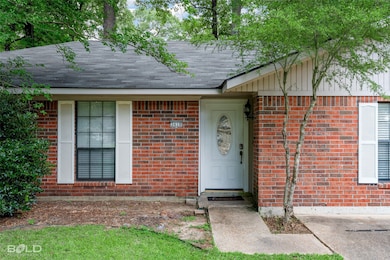 Entrance to property featuring roof with shingles and brick siding