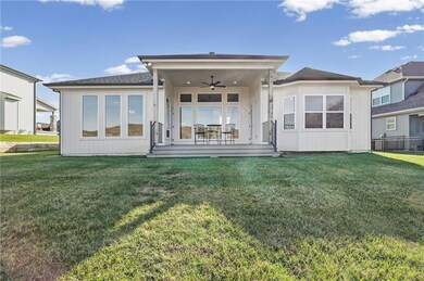 Rear view of property with ceiling fan, a lawn, a deck, and roof with shingles