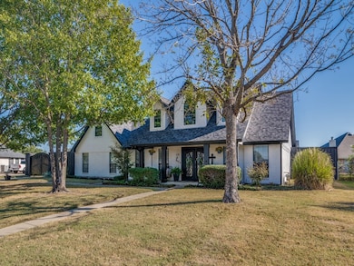 View of front of property with a front lawn, roof with shingles, a porch, and brick siding