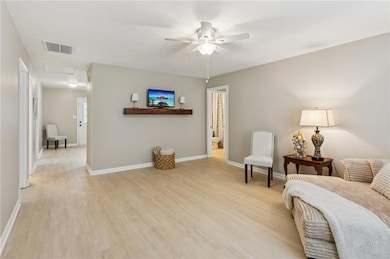 Sitting room with light wood finished floors, attic access, and ceiling fan