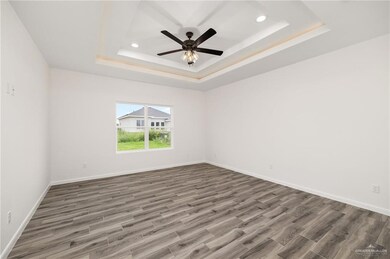 Unfurnished room with wood-type flooring, ceiling fan, and a raised ceiling