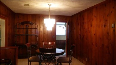 Spacious dining room & kitchen has original wood walls..