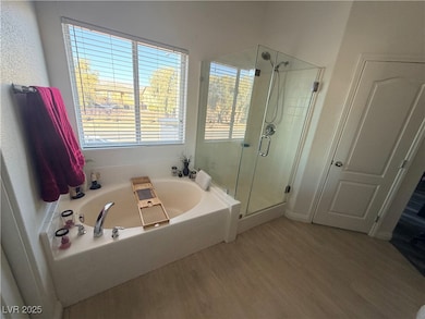 Bathroom featuring a stall shower, a bath, and wood finished floors