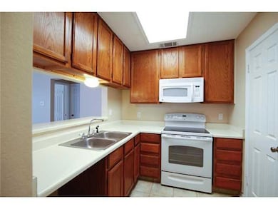 Kitchen with white appliances, a sink, light coun