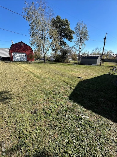 View of grassy yard with a garage and a shed
