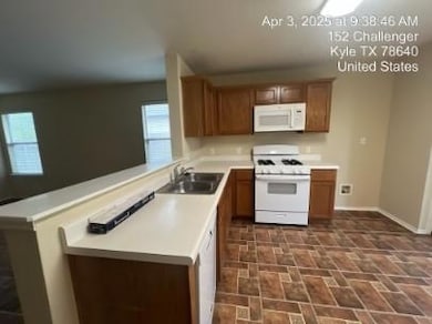 Kitchen featuring white appliances, light countertops, and brown cabinetry