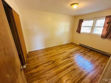 Unfurnished room with a baseboard heating unit and wood finished floors