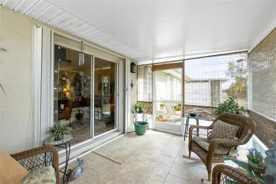 Tiled rear screened porch with patio beyond off slider to Living with hurrican accordion shutters.