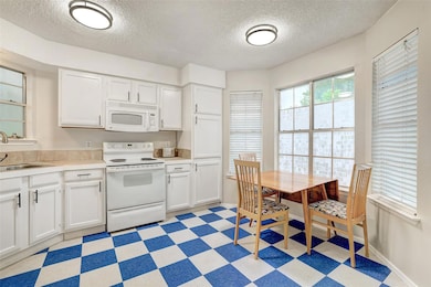 Kitchen with white appliances, light floors, a te