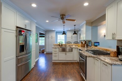 The kitchen has ample cabinet space, a gas cooktop and stove, and a stainless steel farmhouse sink.
