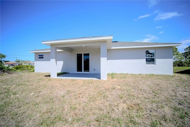 Back of property with stucco siding, a yard, and a patio