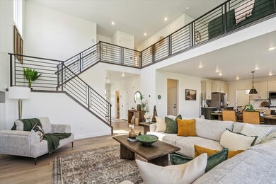 Living area featuring a towering ceiling, light wood finished floors, recessed lighting, and stairs