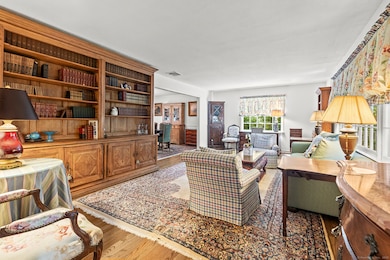 Entrance to the to the Living Room from Foyer, with Built-In Cabinetry, Hardwood Floors, and view of Dining Room