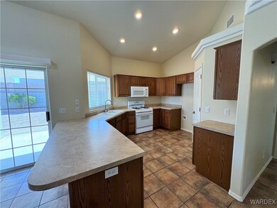 Kitchen with white appliances, a peninsula, light