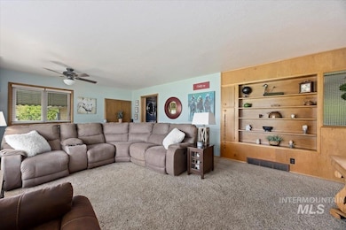 Living room featuring a ceiling fan, carpet, a textured ceiling, and wooden walls