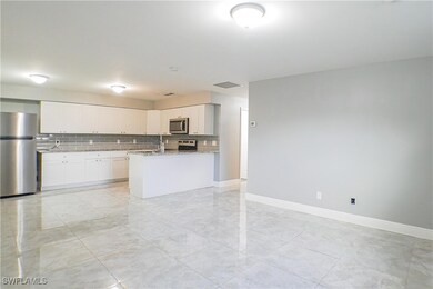 Kitchen featuring white cabinetry, decorative backsplash, stainless steel appliances, and light stone counters