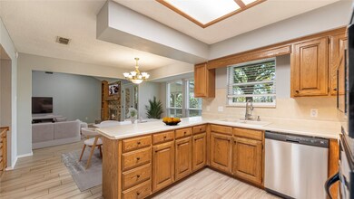 Kitchen featuring open floor plan, a peninsula, dishwasher, light countertops, and hanging light fixtures