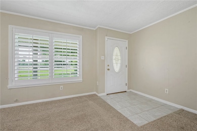 Foyer entrance with light carpet, crown molding, a