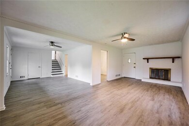 Unfurnished living room with ceiling fan, a brick fireplace, wood finished floors, and stairway