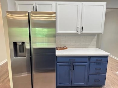 Kitchen featuring white cabinets, light wood-style